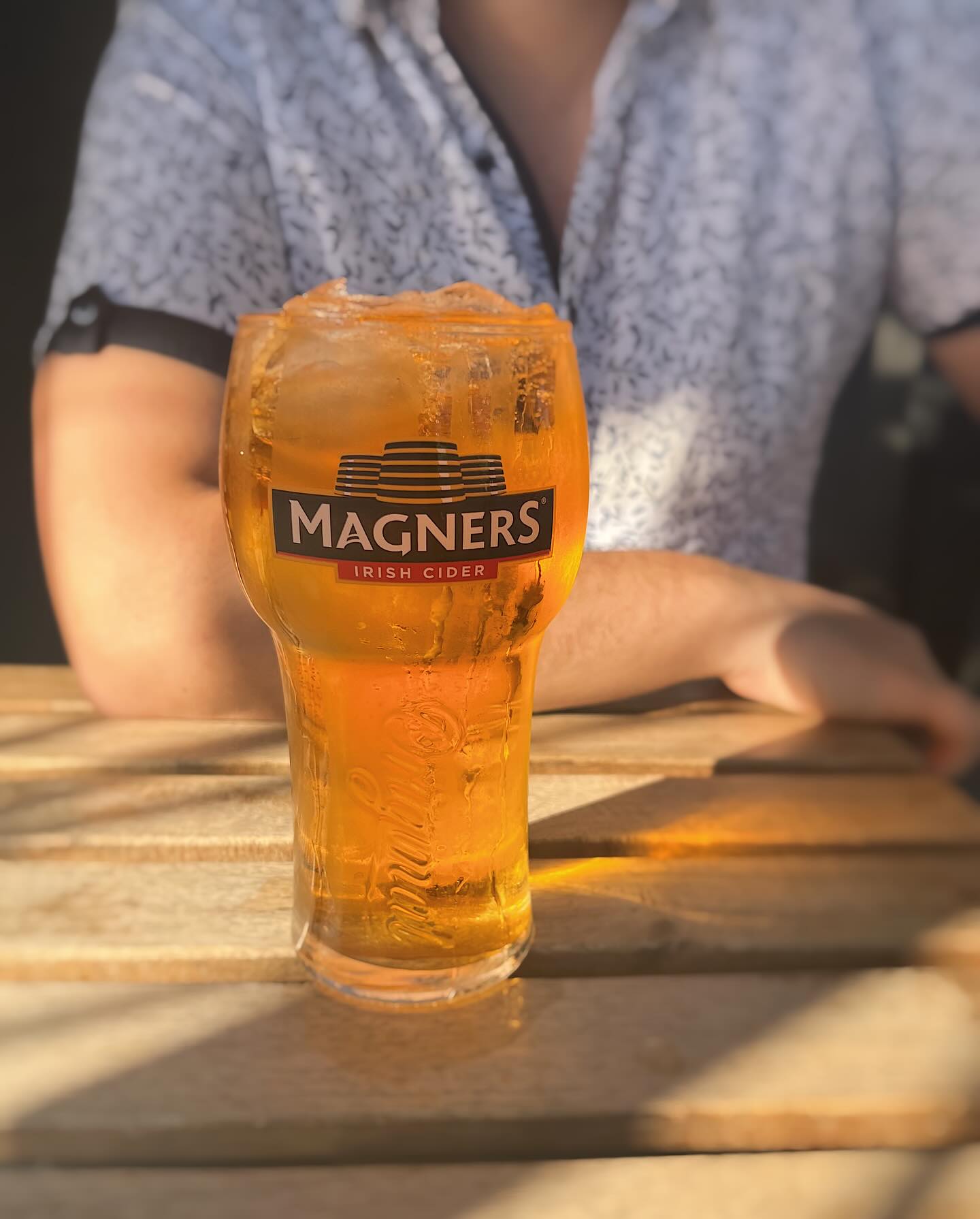 A pint of Magners over ice on a sunlit picnic table on the front patio