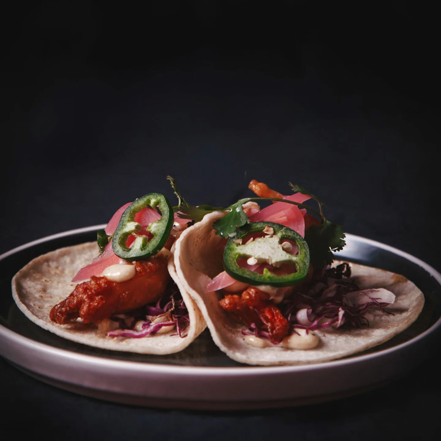 Two beer-battered shrimp tacos with pickled onion, jalapeño and red cabbage